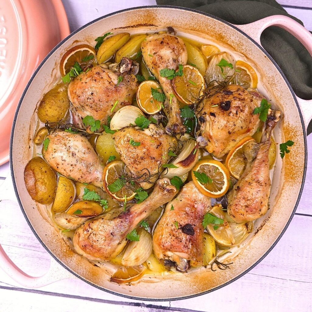 roasted greek chicken with potatoes in a pink shallow cast iron casserole