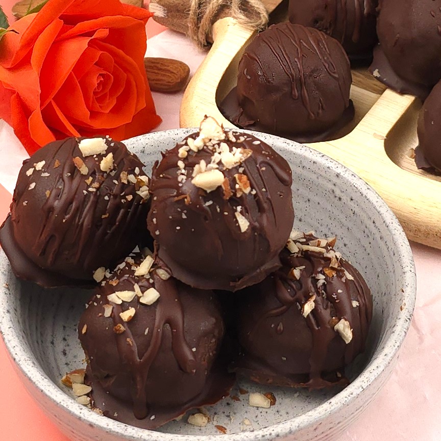 a close look of cocoa energy balls, sprinkled with crushed almonds in a white stoneware bowl