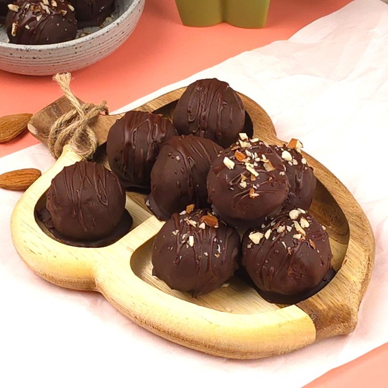 cocoa energy balls in a wooden tray topped with crushed almonds