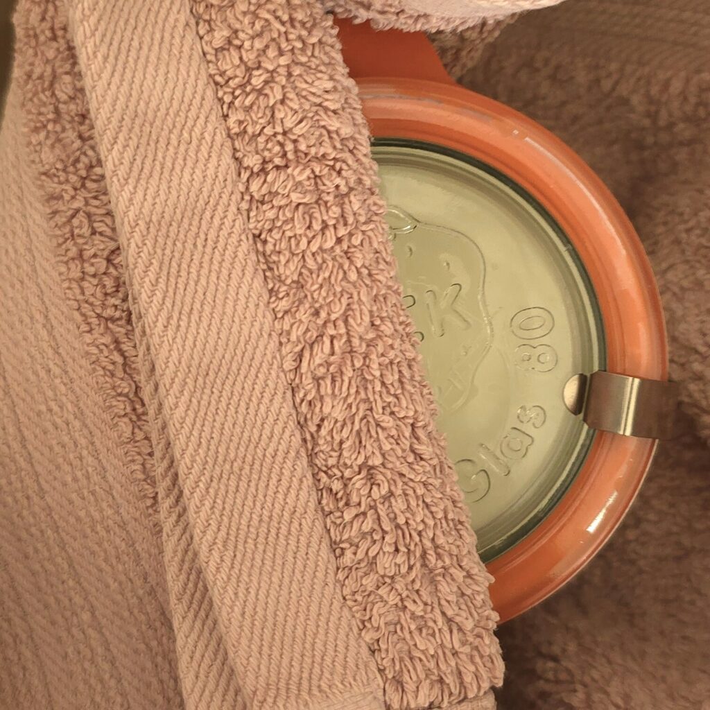 Glass jar wrapped in a warm towel to maintain temperature during yogurt fermentation.