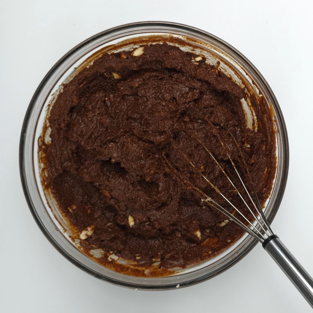 The batter for caprese cake in a glass mixing bowl and whisk
