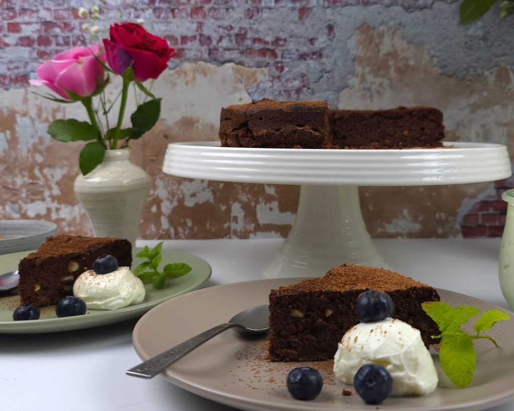 two plates with slices of caprese cake next to a cake stand