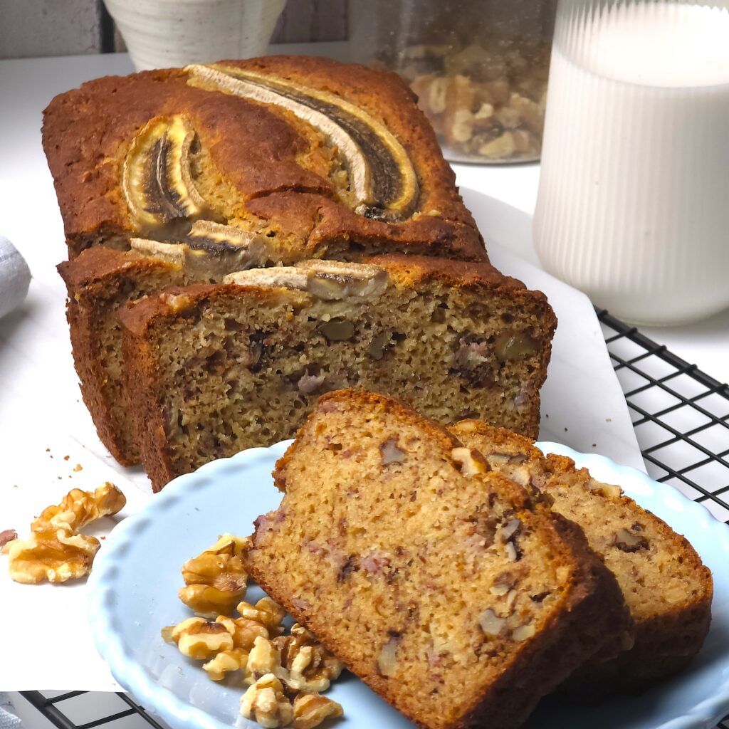 a sliced gluten-free no sugar banana bread next to a blue plate with banana bread slices