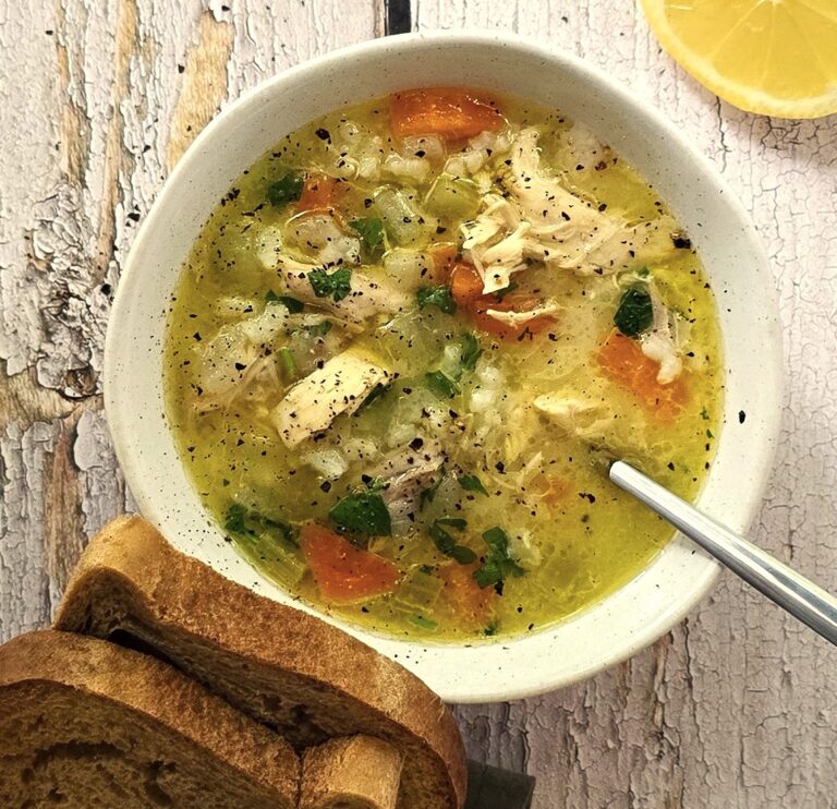 Bowl of creamy gluten-free chicken soup garnished with parsley, served in rustic white ceramic