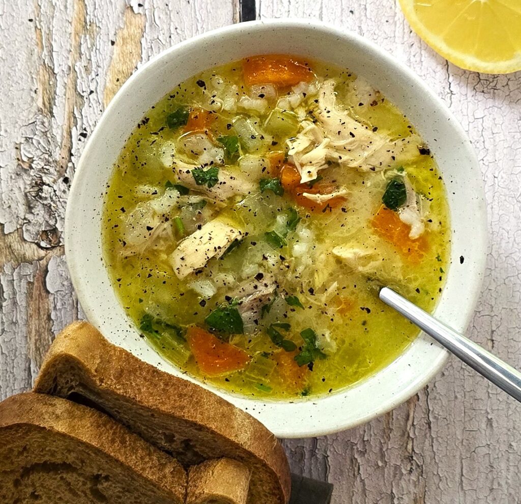 Comforting gluten-free chicken soup ready to serve with fresh parsley and side of gluten-free bread