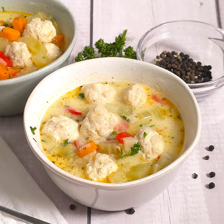 a turkey meatball soup in a white stoneware bowl