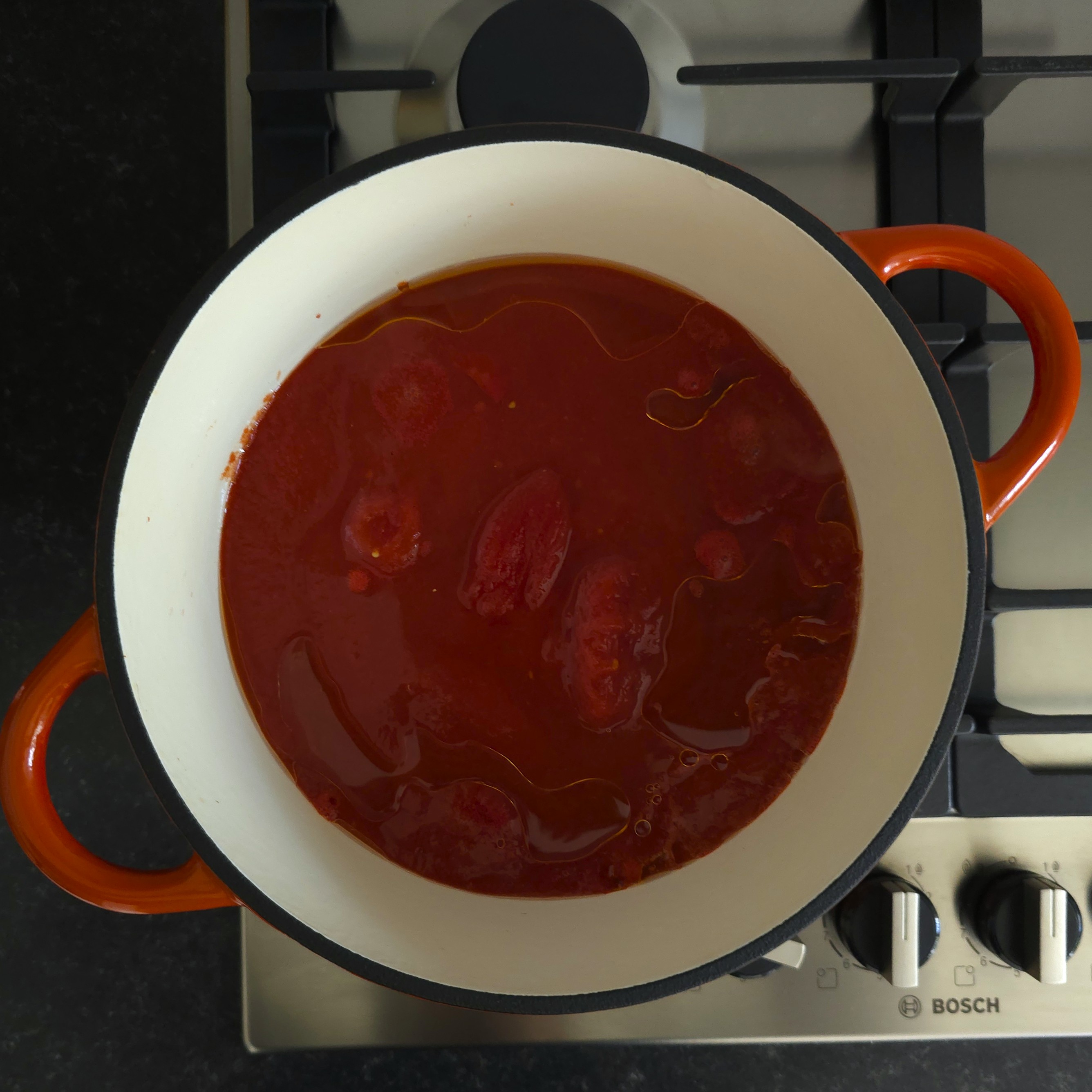 canned tomatoes and oil in a pot 