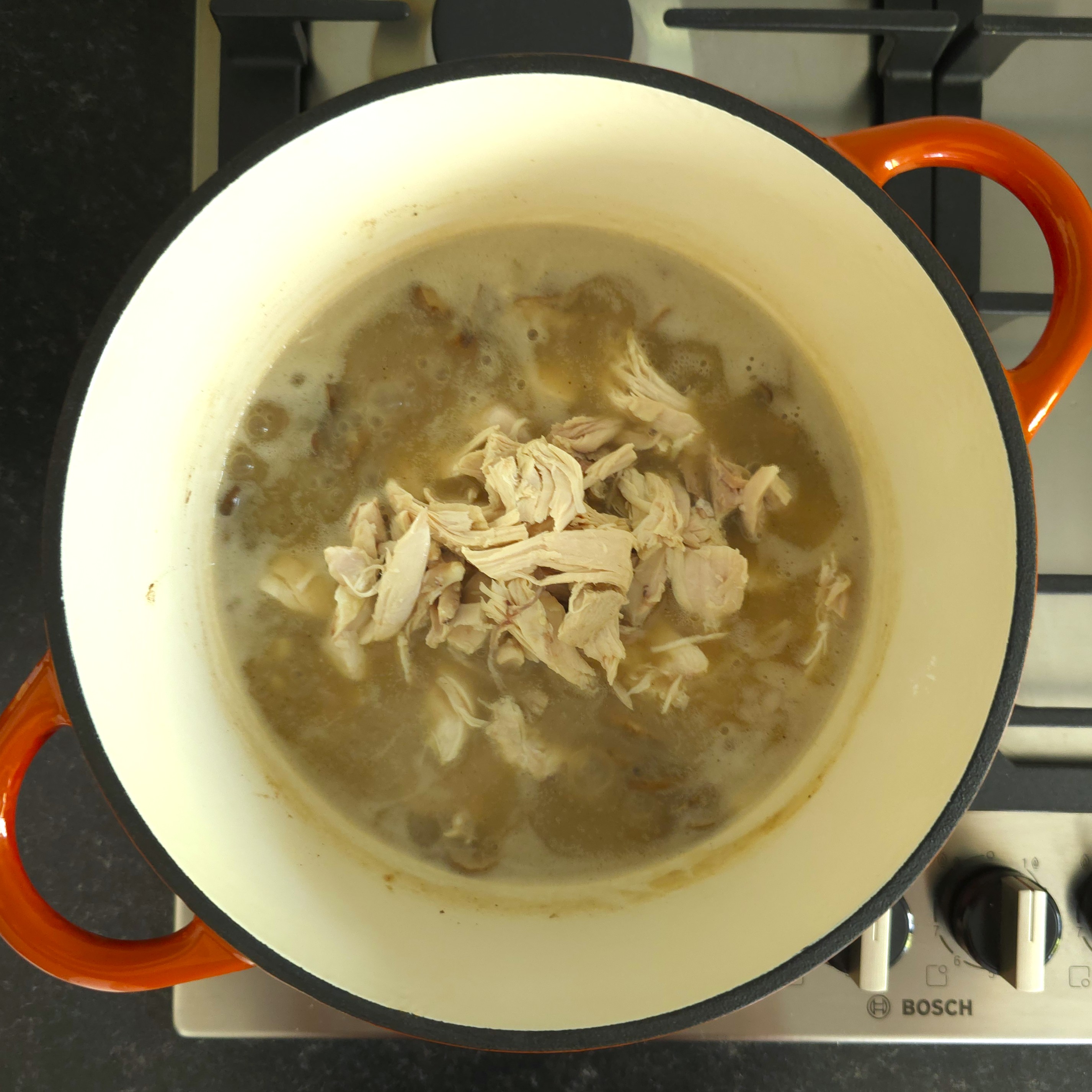 added shredded chicken to mushrooms in a pot