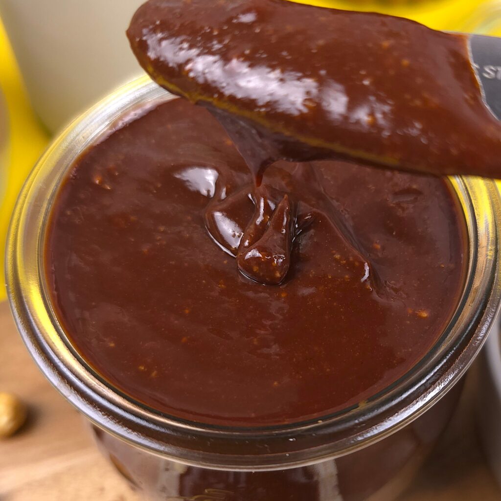 a butter knife over a jar with a homemade hazelnut spread