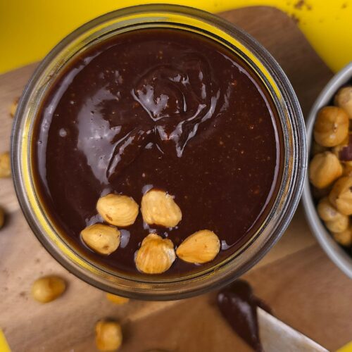 a jar with a homemade nutella topped with roasted hazelnuts