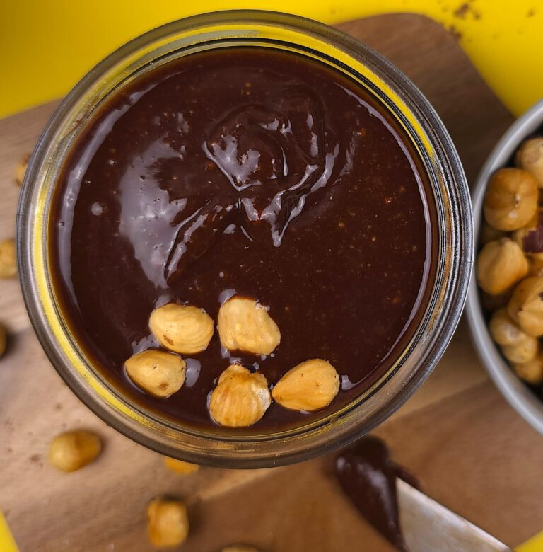 a jar with a homemade nutella topped with roasted hazelnuts