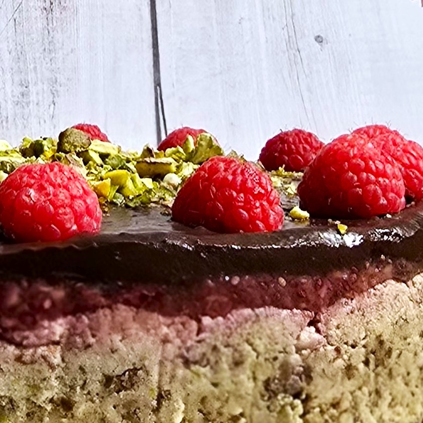 gluten-free no-bake yoghurt tart with avocado chocolate cream topping, decorated with raspberries and pistachios