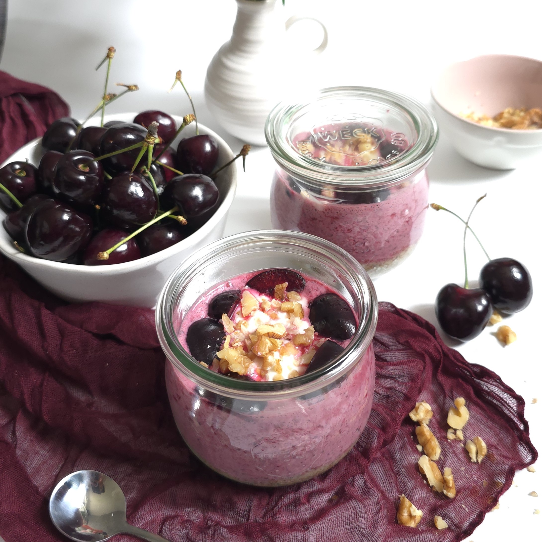 cherry parfait in jars next to fresh cherries in a bowl