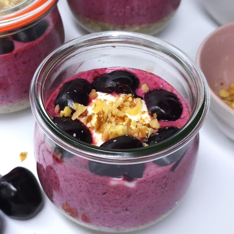 A jar with cherry yoghurt chia parfait topped with halved cherries and crushed walnuts