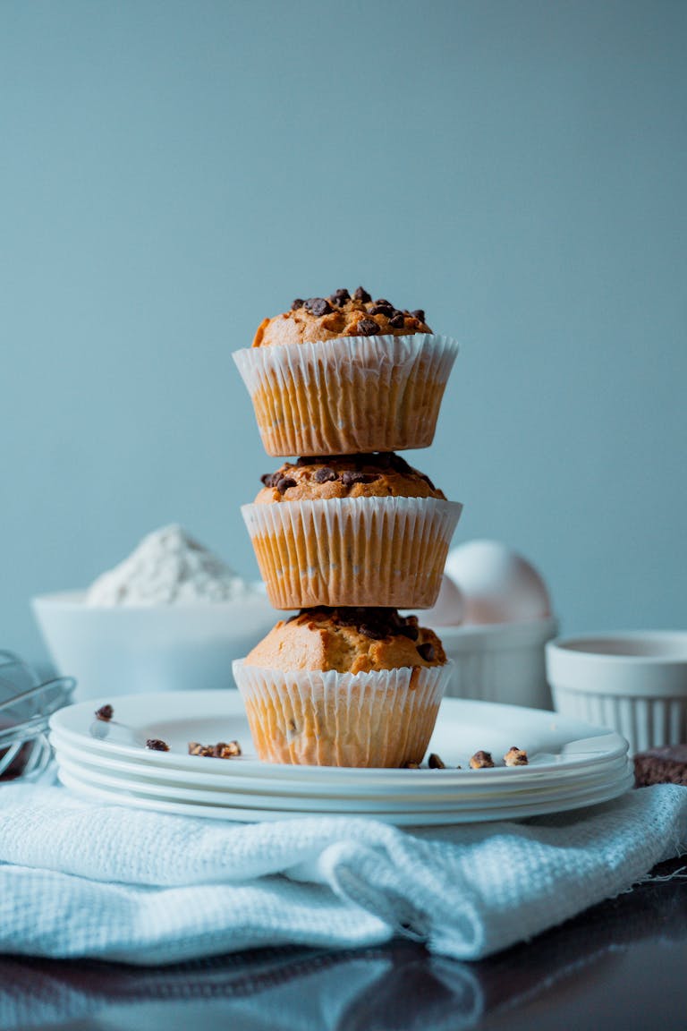 Delicious homemade chocolate chip muffins stacked on plates, perfect for dessert and baking themes.