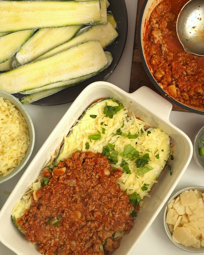 half layered courgette lasagna in a white ceramic baking dish