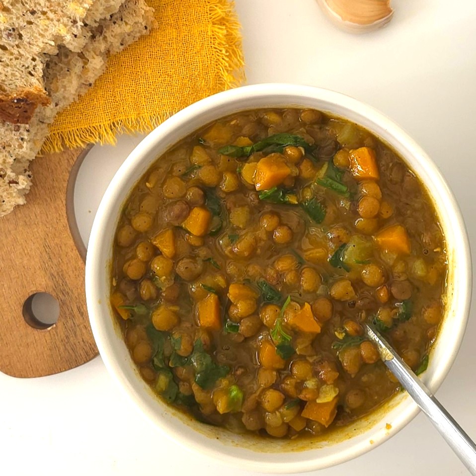 lentil soup in a white bowl and spoon