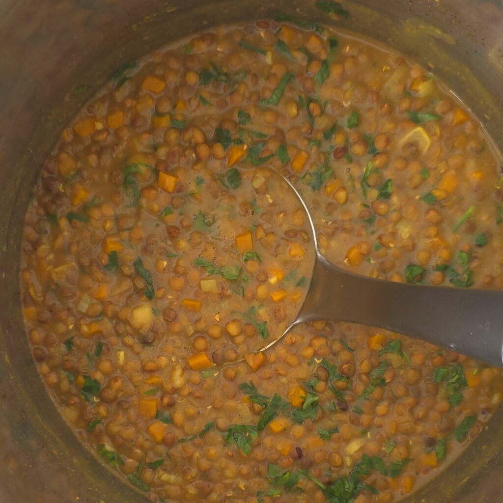 an instant pot with lentil soup and ladle 