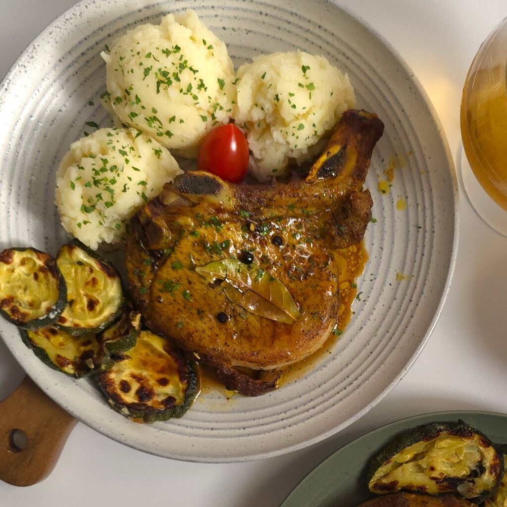 pork chop in a gray plate with potato mash and oven-baked zucchini