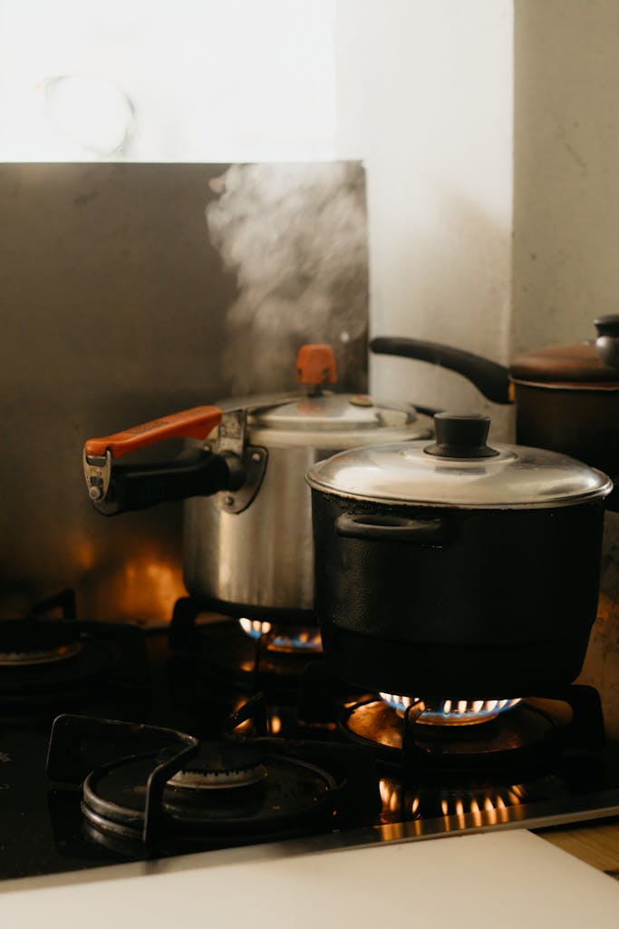 Steaming pots on a kitchen stove with smoke rising in a cozy indoor setting.