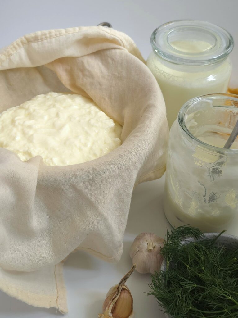 straining yogurt for yogurt garlic dip recipe in a mesh and jars on the side