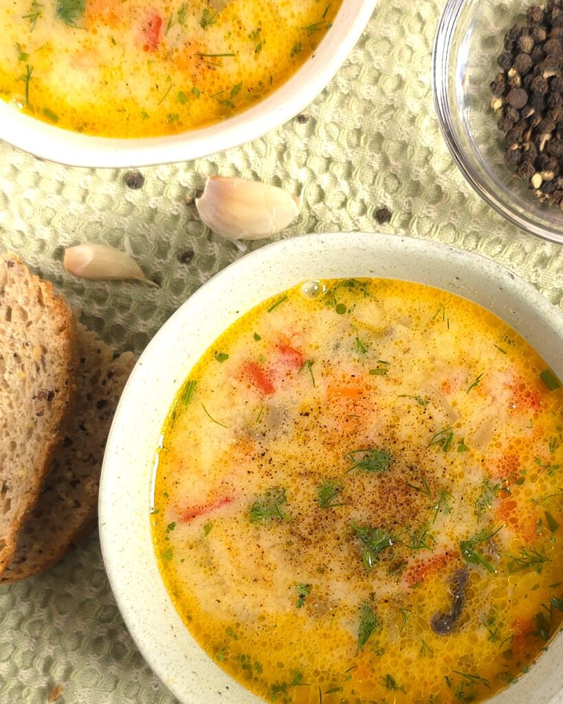 two bowls with vegetable soup, cloves garlic and sourdough gluten-free bread