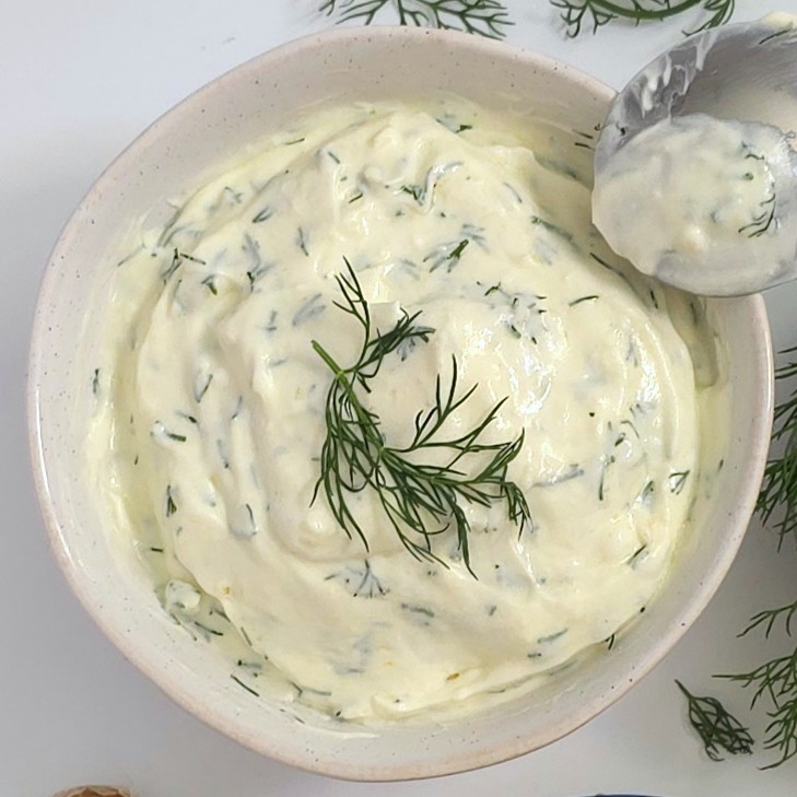 a mixed yoghurt sauce in a white bowl and a spoon