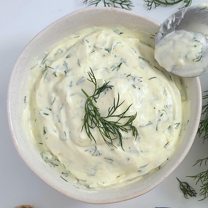 a mixed yoghurt sauce in a white bowl and a spoon