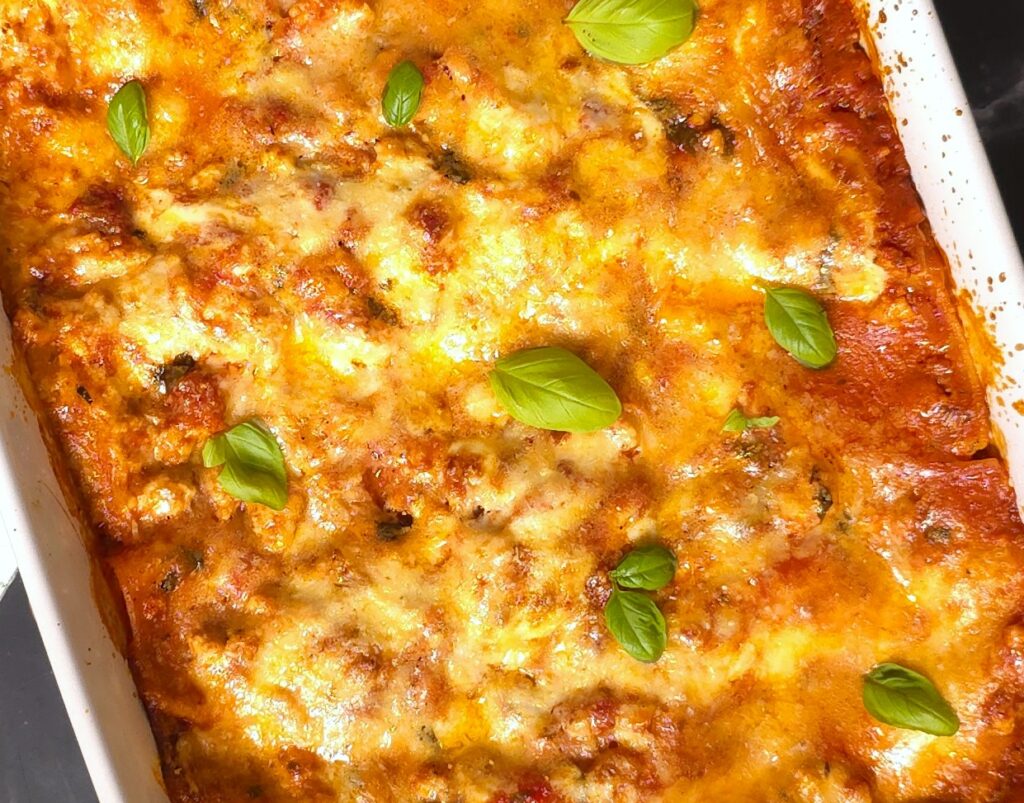 a close look of a gluten-free, lactose-free lasagna in a white ceramic baking dish