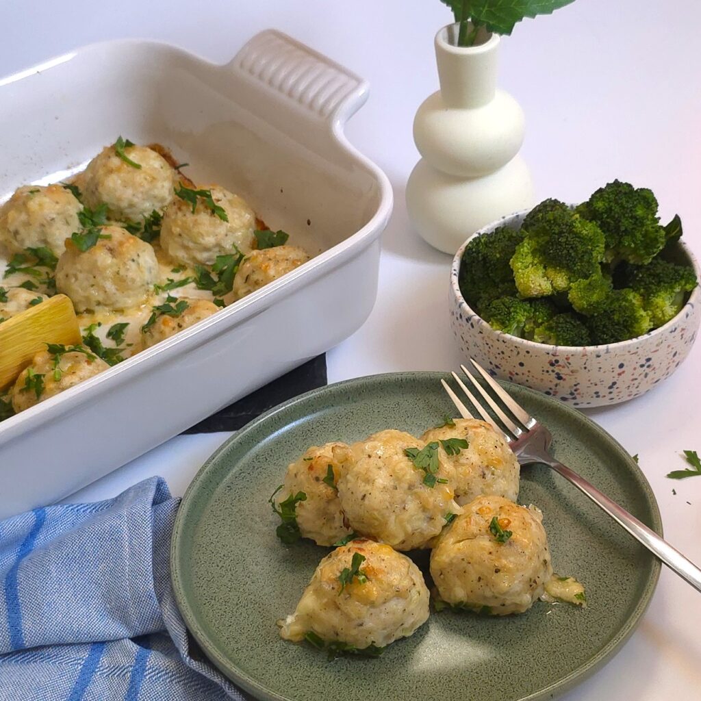 a green plate with healthy oven-baked meatballs net to steamed broccoli