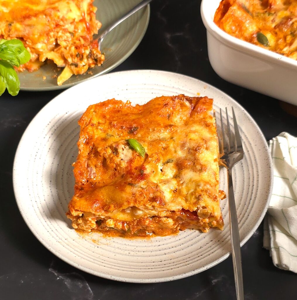 a square of gluten-free, lactose-free lasagna in a white, stoneware plate
