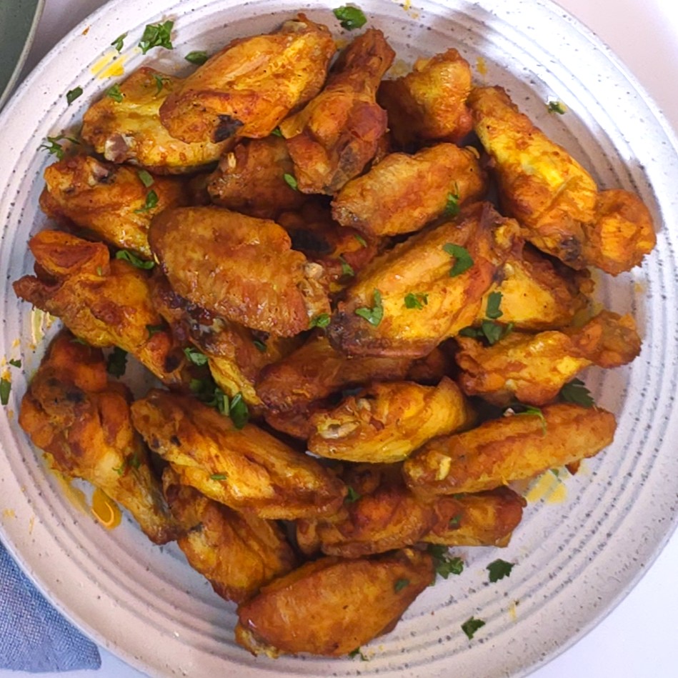 a grey plate with chicken wings, sprinkled with fresh parsley