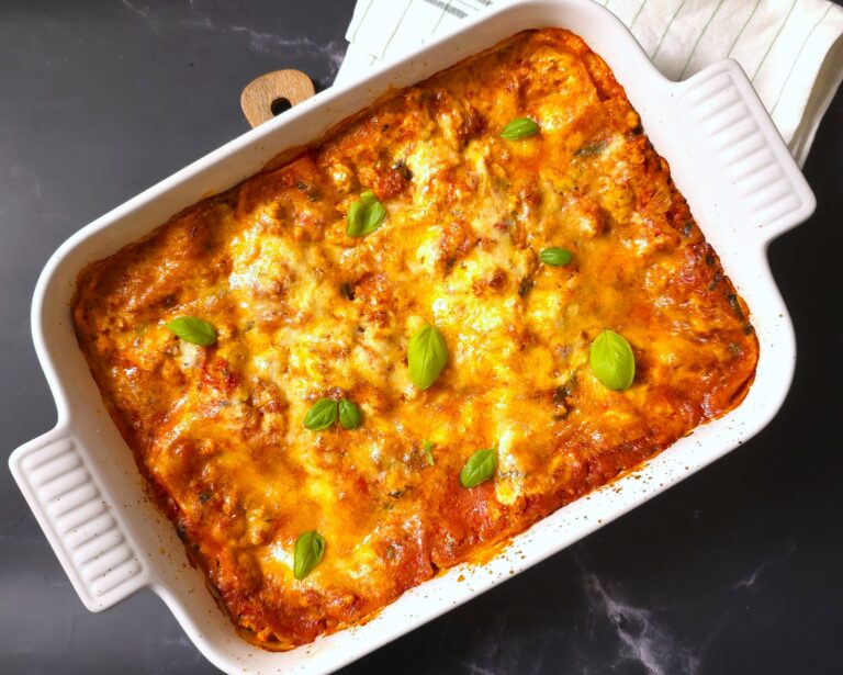 a baked gluten-free, lactose-free lasagna in a white ceramic baking dish
