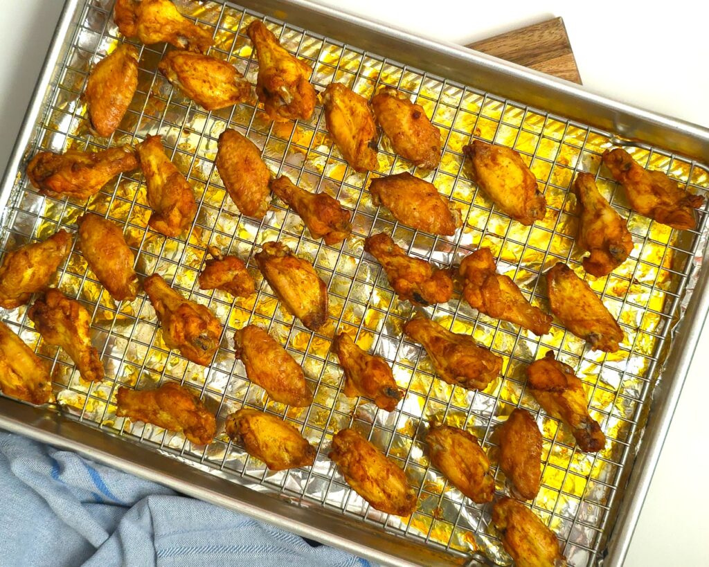 oven-baked golden chicken wings on a baking tray with a n oven-safe grid