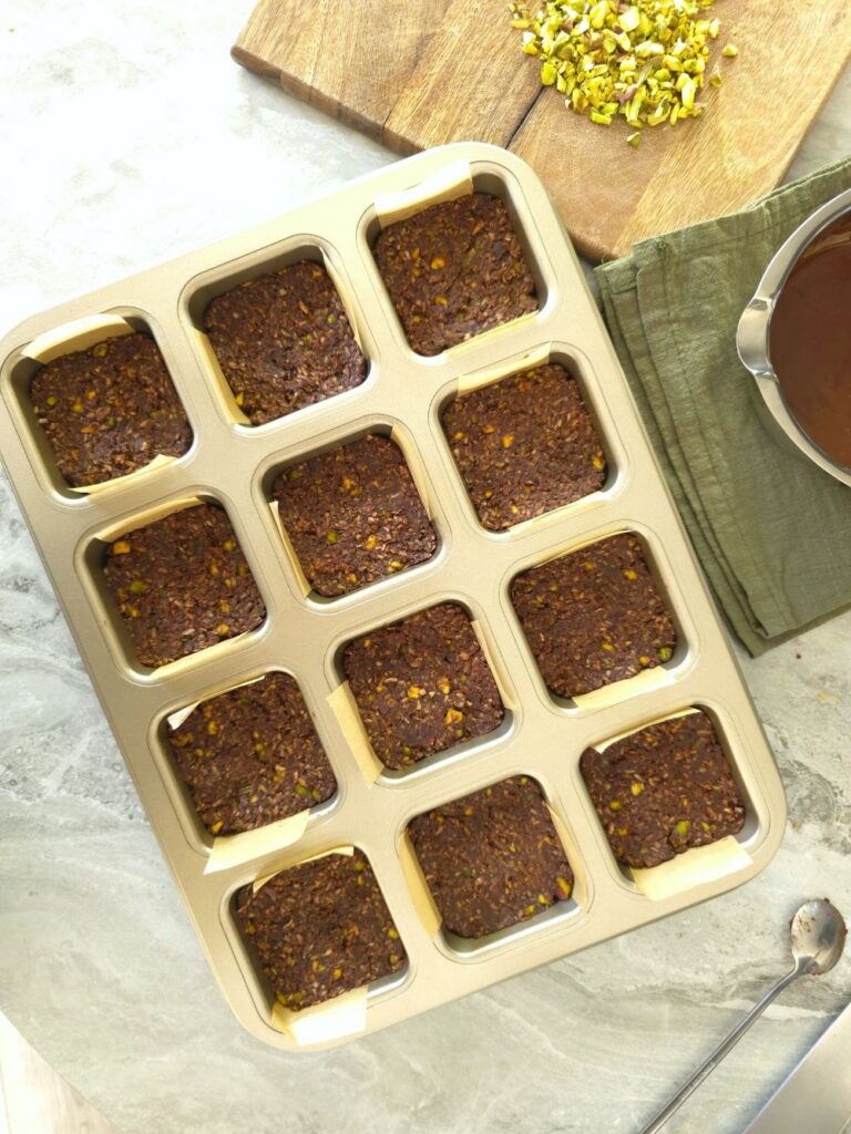 pistachio chocolate squares in a muffin tin