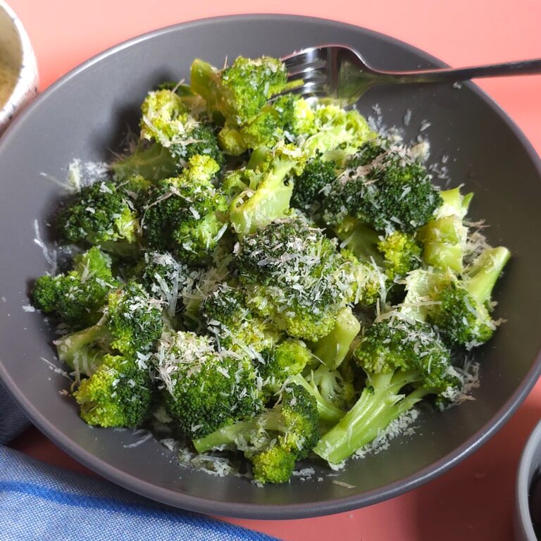 steamed broccoli in a dark grey bowl and grated parmesan on top