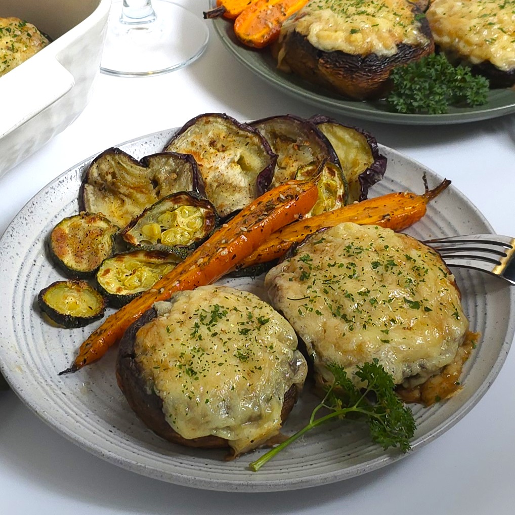 Baked portobello mushrooms stuffed with juicy chicken mince and topped with golden melted cheese, served hot with colourful roasted vegetables.