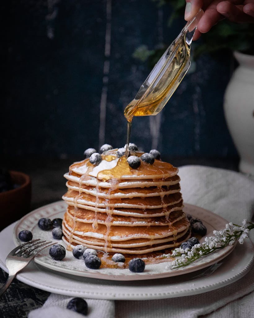 A stack of pancakes topped with blueberries and drizzled with maple syrup for a sweet breakfast treat.