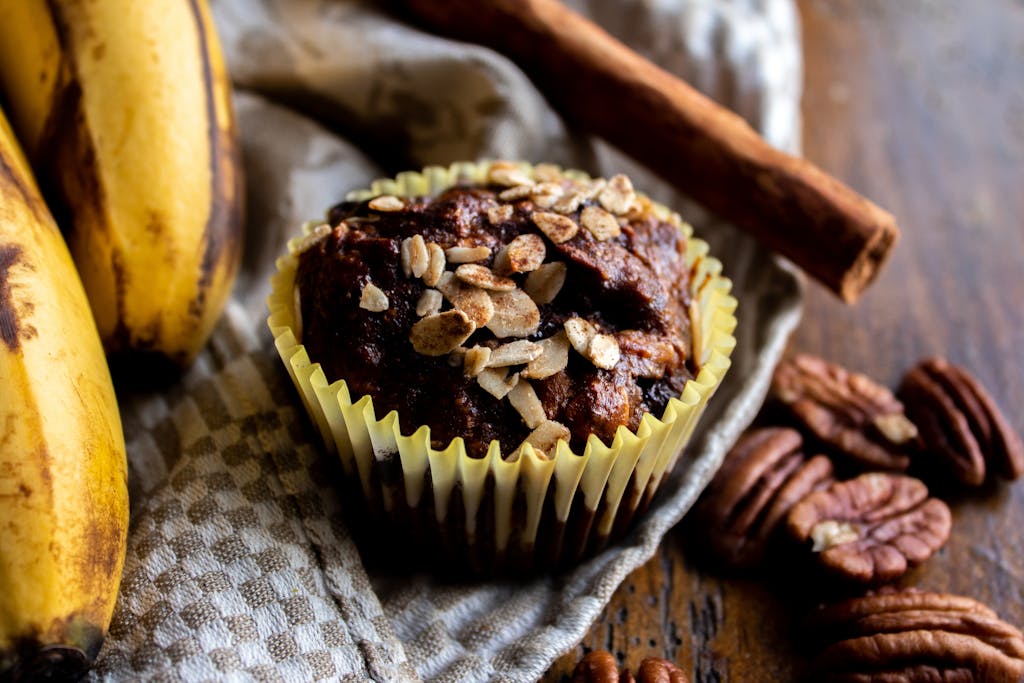 Close-up of a delicious banana oat muffin topped with nuts, perfect for a tasty treat.