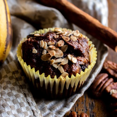 Close-up of a delicious banana oat muffin topped with nuts, perfect for a tasty treat.