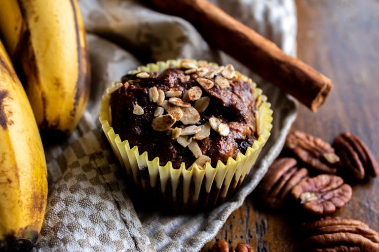 Close-up of a delicious banana oat muffin topped with nuts, perfect for a tasty treat.
