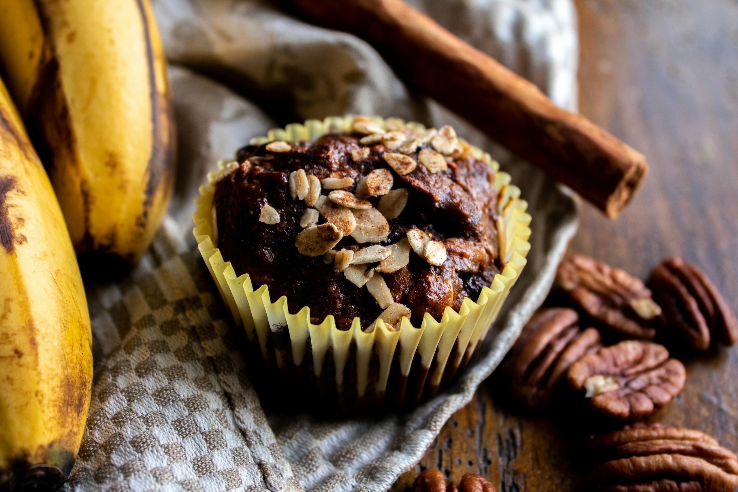 Close-up of a delicious banana oat muffin topped with nuts, perfect for a tasty treat.