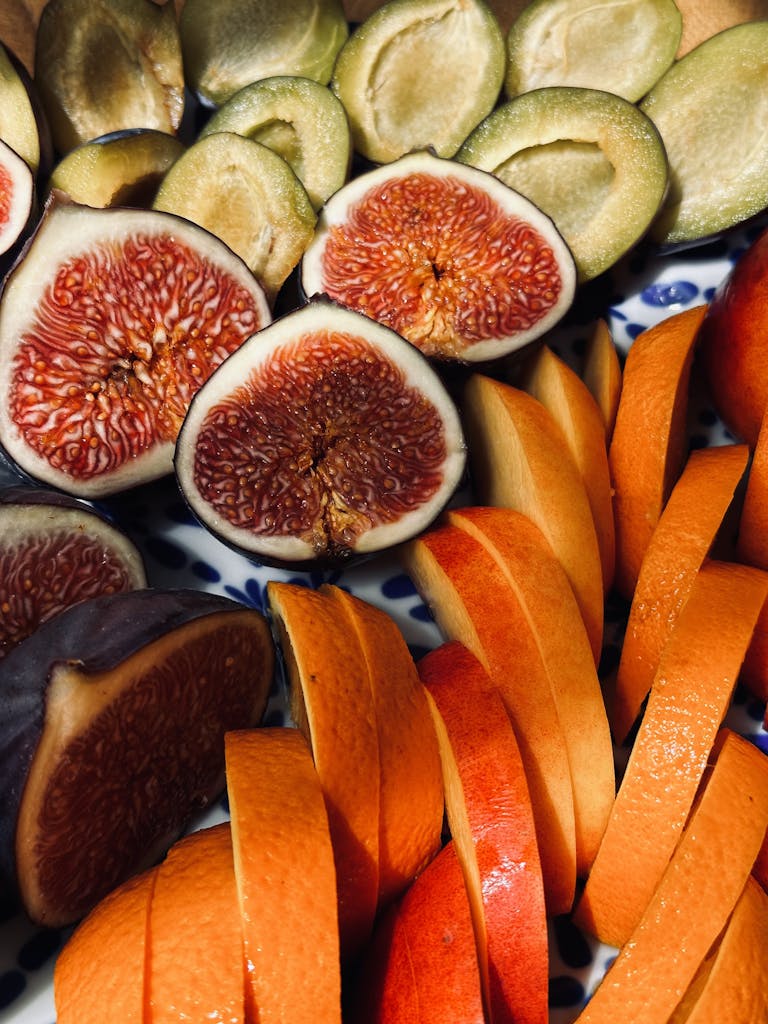 Colorful display of figs, oranges, and mango slices on a decorative plate.