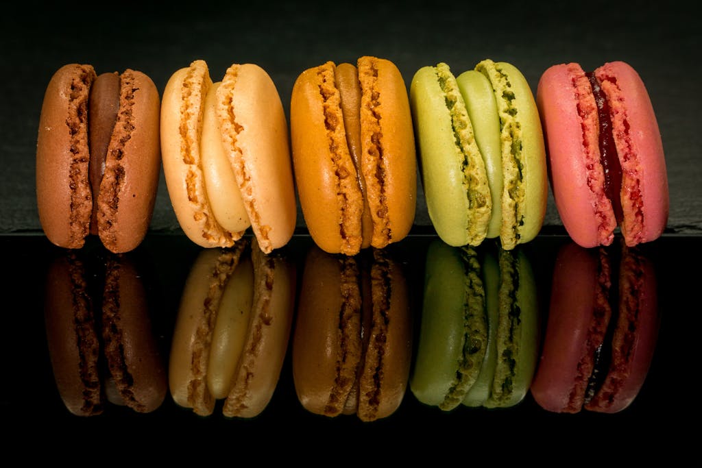 Vibrant macarons in various flavors aligned on a glossy black backdrop.