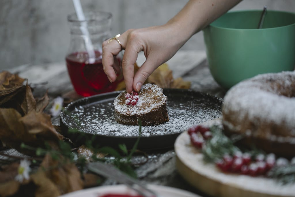 A hand carefully decorates a homemade cake with fresh berries, creating a delicious dessert.