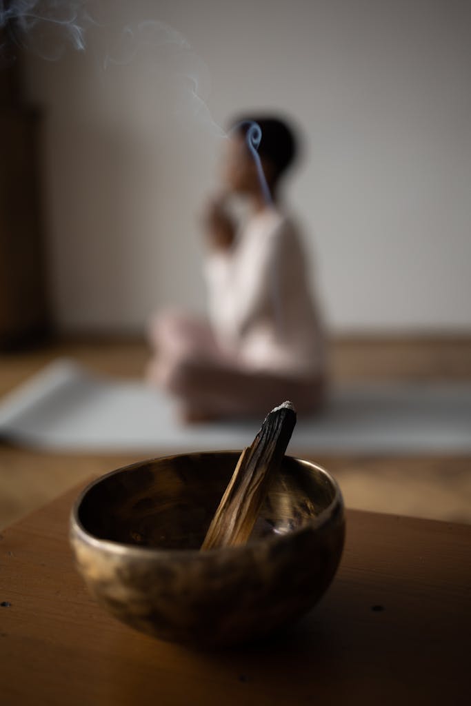 A serene moment of mindfulness featuring incense in a singing bowl during yoga practice.