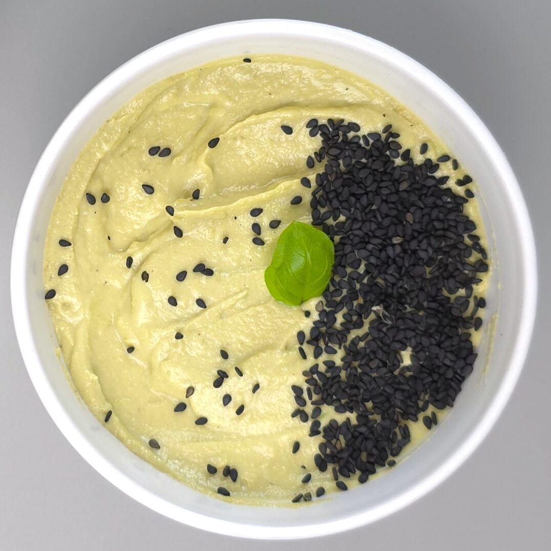 a ceramic bowl of avocado tahini dip sprinkled with black sesame