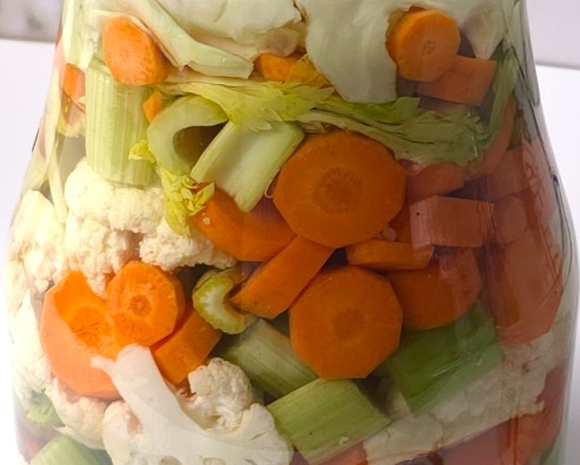 a close look to a jar with chopped vegetables and brine, ready for fermentation
