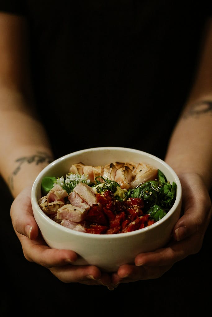 Close-up of a nutritious bowl held by hands, featuring fresh and healthy ingredients.