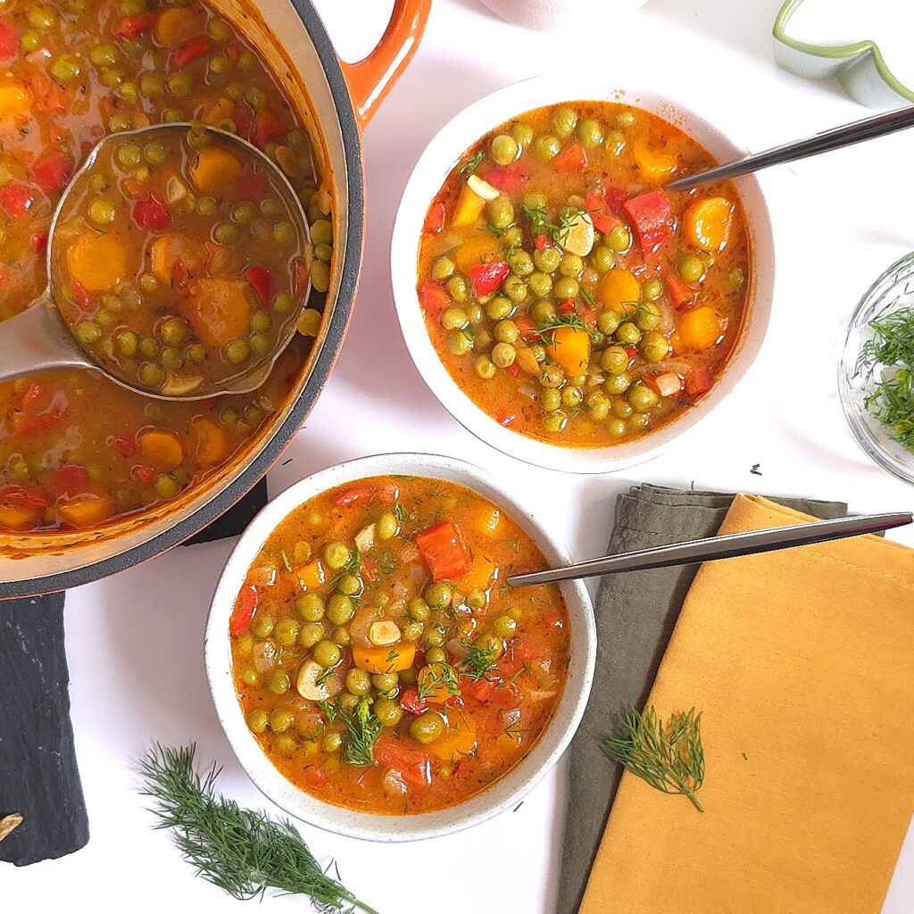 green peas stew recipe in two stone whare bowls next to a cast-iron pot
